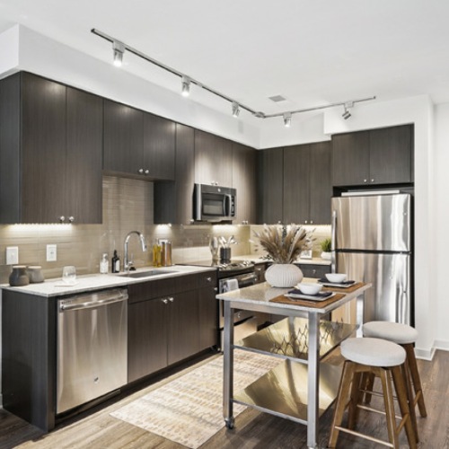 Apartment kitchen at The Daley at Shady Grove featuring stainless steel appliances, quartz countertops, large island, and modern cabinetry in Rockville, Maryland